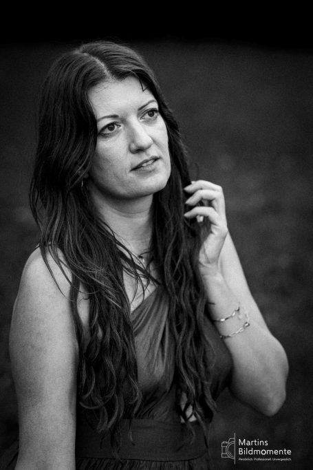 Frau mit langen, dunklen Haaren in einem nachdenklichen Moment, Schwarz-Weiß-Foto.