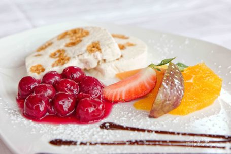Dessertteller mit Eis, Beeren, Fruchtscheiben und Schokoladensauce.
